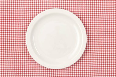 Kırmızı işaretlenmiş masa örtüsü üzerinde beyaz boş tabak