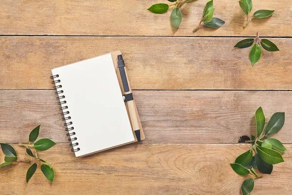 Top view green leaves with notebook with space for text on wood. — Stock Photo, Image