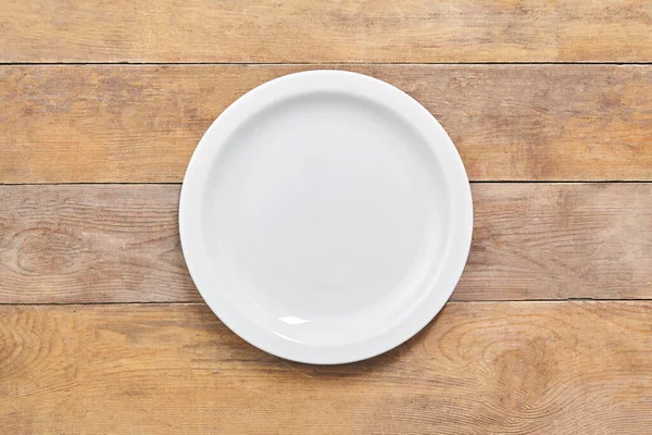 Empty white plate on wooden table. Top view. — Stock Photo, Image