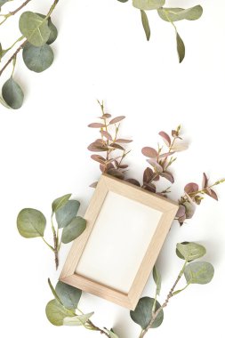 Beyaz masa arkaplanında boş kağıt ve dal yaprağı olan masaüstü maketi.