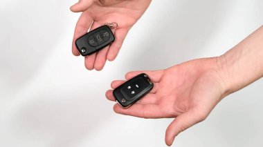 A man offers two car keys. Another picks and takes one. Close up.