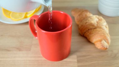 Sıcak kahve meşe ağacının üzerine kırmızı fincana dökülüyor. Kapat..