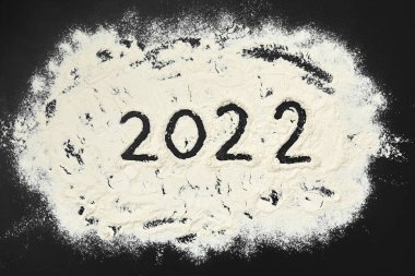 2022 numaralı metin, siyah ahşap zemin üzerinde undan yapılmış. Üst görünüm
