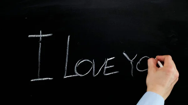 Hand writes with chalk I love you on blackboard. Close up. — 图库照片