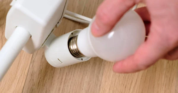 Mans Hands Vervanging van een gloeilamp in lamp. Close-up. — Stockfoto