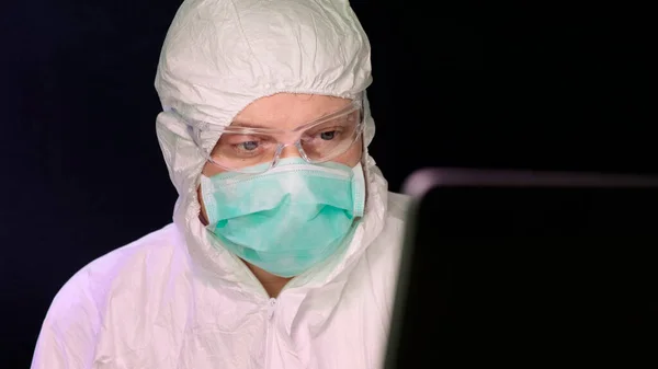 Portrait of masked laborant work on laptop.