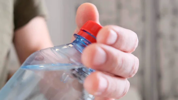 Frauenhände öffnen eine Wasserflasche im Zimmer. Nahaufnahme. — Stockfoto