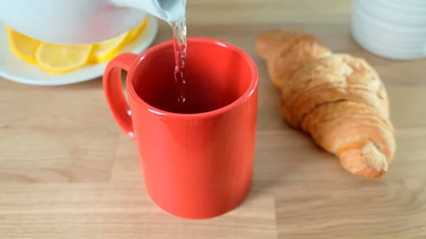 Café caliente vertiendo a la taza roja en la mesa de roble. De cerca. . — Foto de Stock