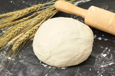 Siyah arka planda buğday kulaklı taze hamur. Kapat..