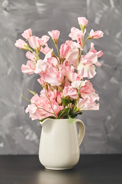 Rosa Blume in der Vase auf schwarzem Tisch auf grauem Hintergrund. Nahaufnahme — Stockfoto