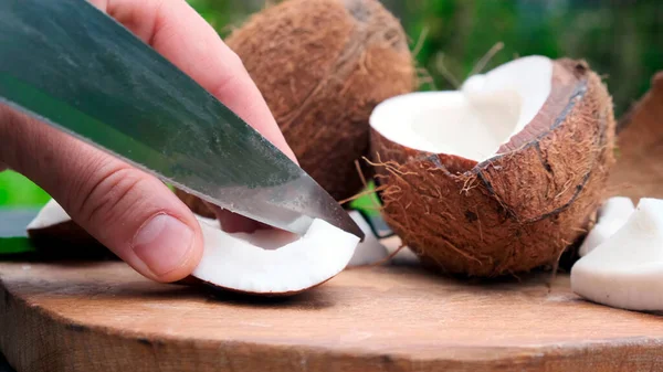 Ręka z nożem w kawałkach połamanego tropikalnego orzecha kokosowego. — Zdjęcie stockowe