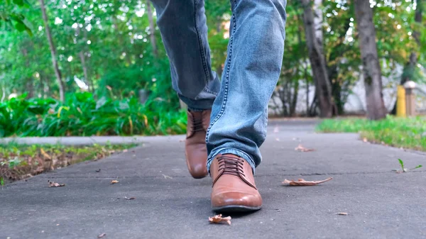 View of mans walking legs in blue jeans, brown leather shoes. — Stock Photo, Image