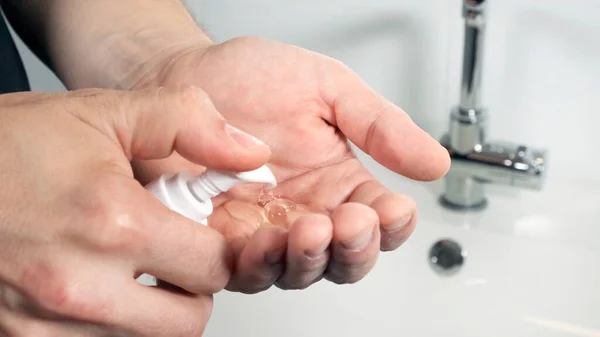 Ein Mann im Badezimmer drückt sich Seife oder Creme auf die Hand. — Stockfoto