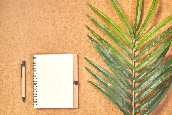 Penna, preparata a scrivere su taccuino finto in vista dall'alto con foglie tropicali . — Foto Stock