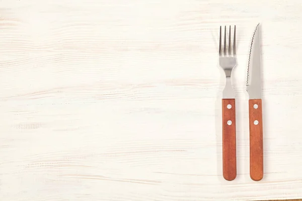 Fork and knife on wooden table with copy space. Top view. — Stock Photo, Image