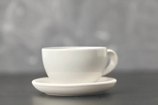 Una taza blanca en la mesa negra. Sobre fondo gris — Foto de Stock