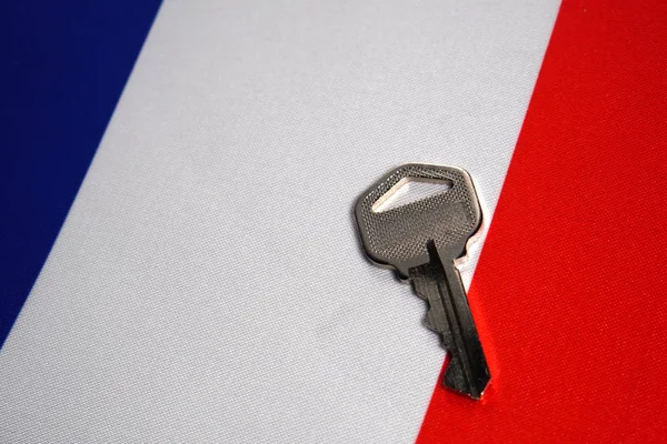 Silver key on the flag of France. Close-up, copy space