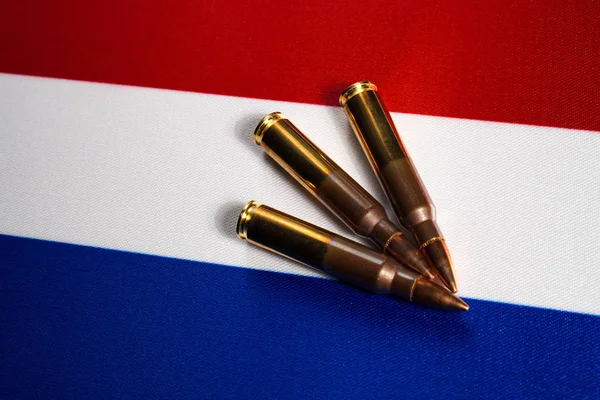 Three rifle cartridges on the flag of Netherlands. Close-up, copy space — Stock Photo, Image