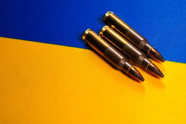Tre cartucce di fucile sulla bandiera dell'Ucraina. Primo piano, copia spazio — Foto Stock