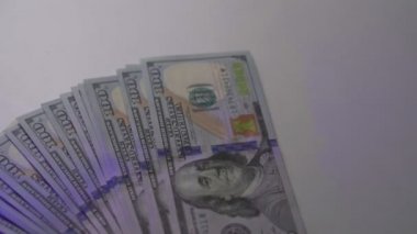 Lots of hundred-dollar bills and handcuffs on a white table. Bribery, theft, robbery concept