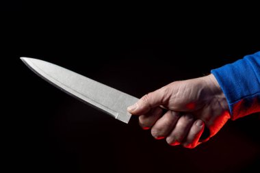 Kitchen knife in a mans hand close-up on a black background