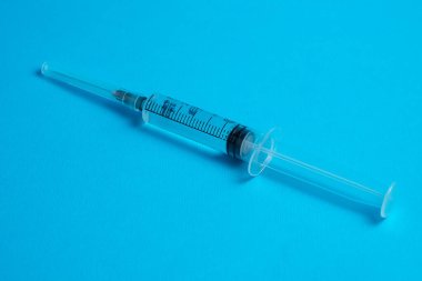 Mavi arka planda aşısı olan tıbbi bir şırınga. Boşluğu kopyala