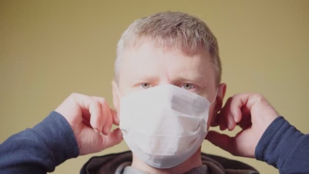 En man tar av sig en medicinsk mask. Pandemisk COVID-19 — Stockvideo