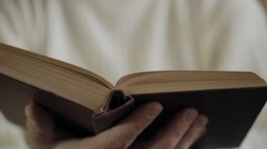 Adam eski kitapları okuyor, elleriyle yakın plan. Yumuşak odak