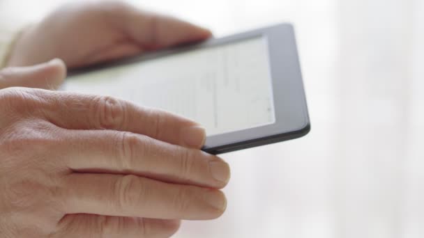 Homme blanc lit un e-book près de la fenêtre, gros plan. Concentration douce — Video