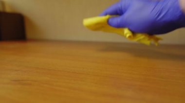Bir adam ahşap bir masanın tozunu sildi.