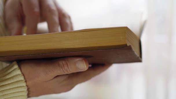 O homem está lendo livro antigo, close-up com as mãos, vista lateral. Foco suave — Vídeo de Stock