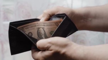 Elinde bir dolar olan siyah deri bir cüzdan. İflas ve Yoksulluk Konsepti