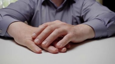 Sinirli bir memur ya da işadamı parmaklarını masaya vuruyor. Gri gömlekli bir adamın elleri masaya vuruyor, yakın plan.