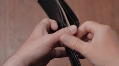 Elinde bir dolar olan siyah deri bir cüzdan. İflas ve Yoksulluk Konsepti