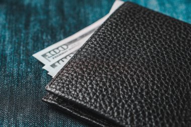 İçinde banknotlar ve kot pantolon olan siyah, hakiki deri bir cüzdan. Yumuşak odak