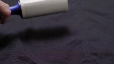 Birisi temizlik silindiri ile giysileri temizliyor. Temizlik için silindiri olan bir adamın elleri.