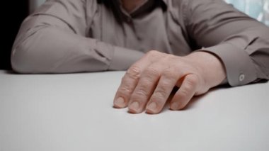 Kızgın bir tezgahtar ya da iş adamı yumruğunu masaya vurur. Gri gömlekli bir adamın yumruğu masaya vuruyor, yakın plan.