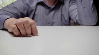 Kızgın bir tezgahtar ya da iş adamı yumruğunu masaya vurur. Gri gömlekli bir adamın yumruğu masaya vuruyor, yakın plan.