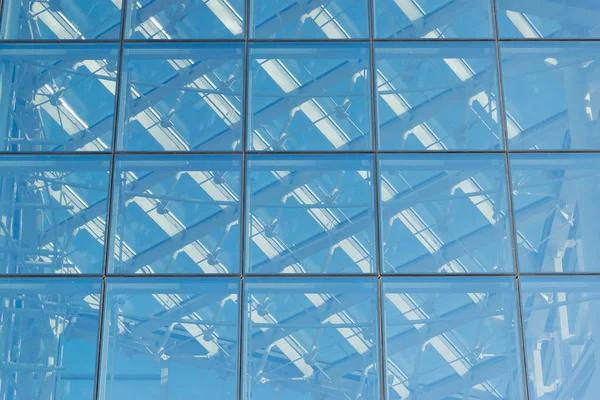 Glass transparent windows on the facade of a modern high-rise office or commercial building in the center of a big city reflect the blue sky