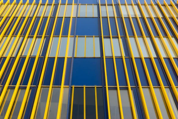 Geometric color elements of the building facade with planes, lines, corners with highlights and reflections for the abstract background and texture of blue, yellow, orange, gray colors. Place for text