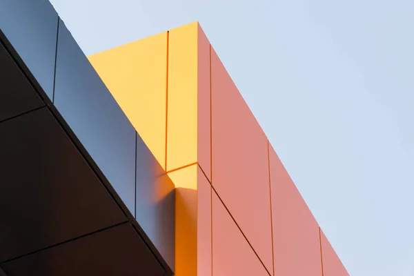 Geometric color elements of the building facade with planes, lines, corners with highlights and reflections for an abstract background and texture of gray, orange colors. Place for text
