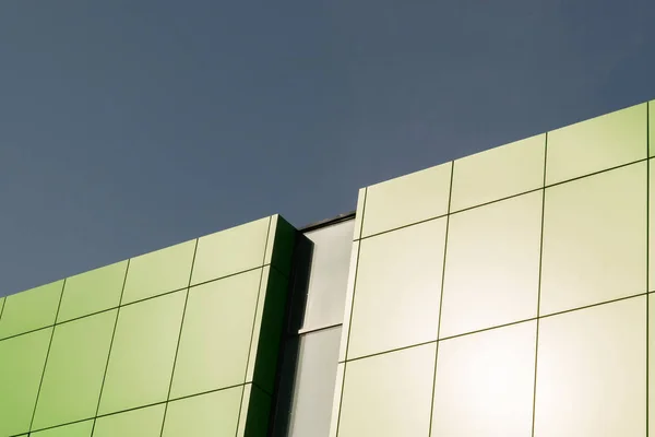 Geometric color elements of the building facade with planes, lines, corners with highlights and reflections for the abstract background and texture of green, light green, blue colors. Place for text