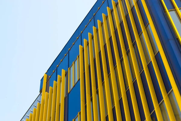 Geometric color elements of the building facade with planes, lines, corners with highlights and reflections for the abstract background and texture of blue, yellow, orange, gray colors. Place for text