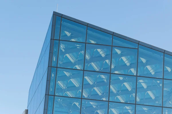 Glass transparent windows on the facade of a modern high-rise office or commercial building in the center of a big city reflect the blue sky