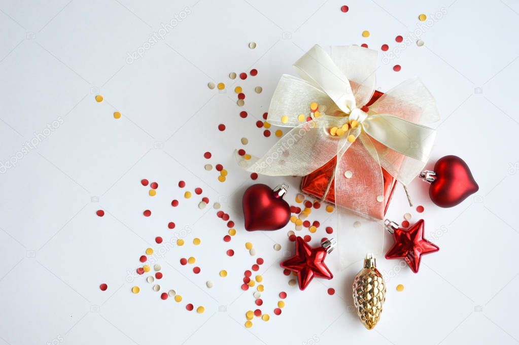 Red gift box. Bow of satin ribbon, confetti and Christmas decorations for the decor for the celebration of New year and Christmas.