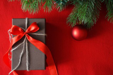 Kırmızı arka planda ladin yeşili dallar ve kırmızı top, Noel oyuncağı. Mutlu yıllar ve mutlu Noeller. Tatil için kartpostal. Kırmızı fiyonklu hediye kutusu.