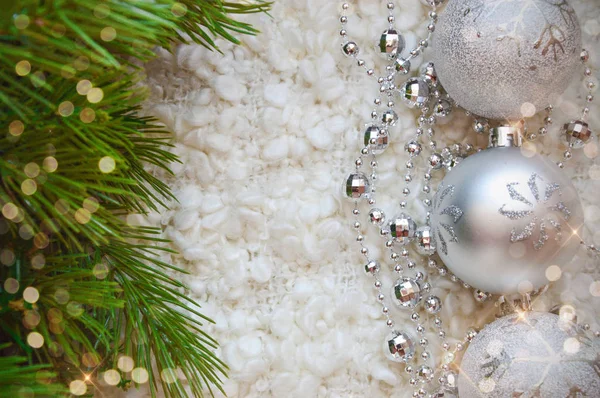 圣诞和新年快乐的装饰品 银色的 圣诞舞会和白色舒适毛毯上的珠子 寒假快乐 祝贺你的背景 圣诞树装饰用的灰色球 和绿树的枝条 — 图库照片