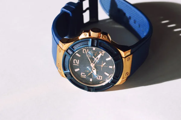 Beyaz arka planda şık bir mavi kol saati. Mavi ve altın rengi yuvarlak arama.