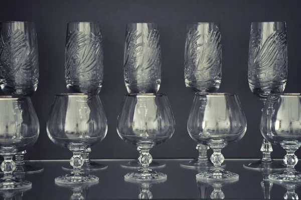 Karanlık bir arka planda alkol için gözlük. Kristal tabaklar.