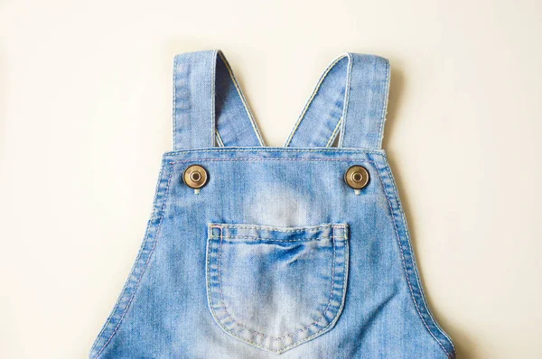 Beyaz bir arkaplanda kot bir tulumun askıları..